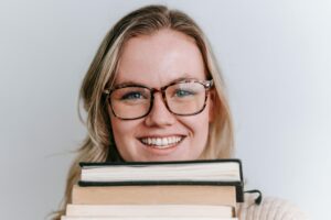 ancestry investigator, genealogy services, discover your family tree, a woman smiling with glasses holding a stack of books